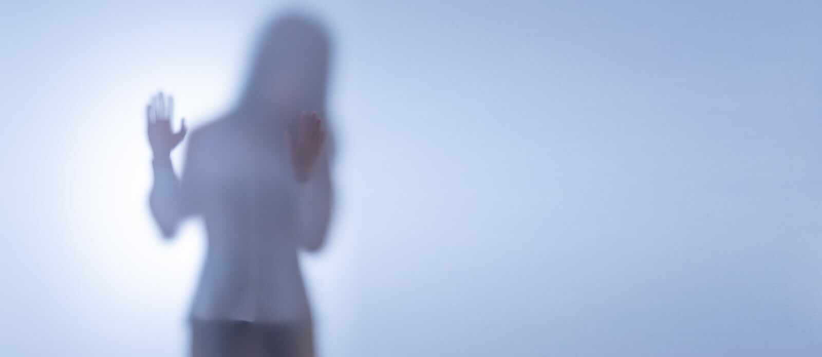 A woman stands behind distorted glass. Feeling like the emotional abuse you have suffered through is too much to handle? It may be time to speak with a trauma therapist in Austin, TX and start trauma therapy. 