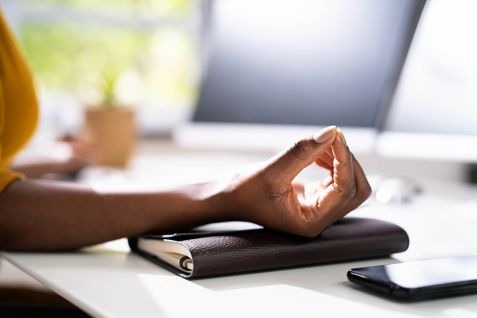 A woman sits at her desk and meditates with her hands on a book. Want to learn how to heal from your trauma? Online therapy may be your best option. Our online therapist can help you navigate your trauma. Try online therapy in Texas today!