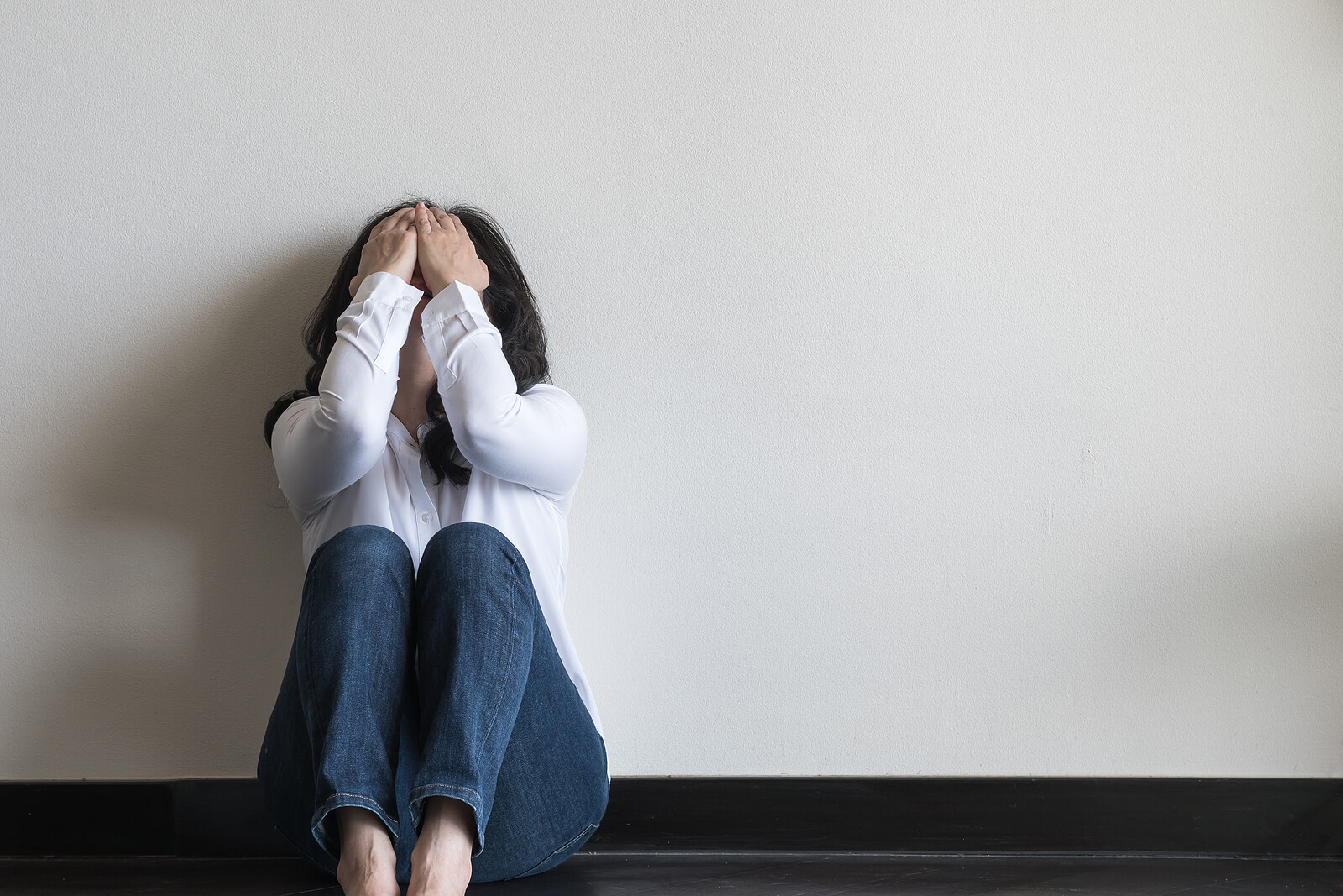 A woman sits leaning against a wall crying into her hands. Has your developmental trauma stopped you from moving forward with your life? It might be time to start trauma therapy in Austin, TX. Speak with a trauma therapist to find out more today!