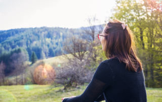 A woman sits in nature thinking. Want to know how depth therapy in Houston, TX can help you? Learn more about Online therapy in Texas today!