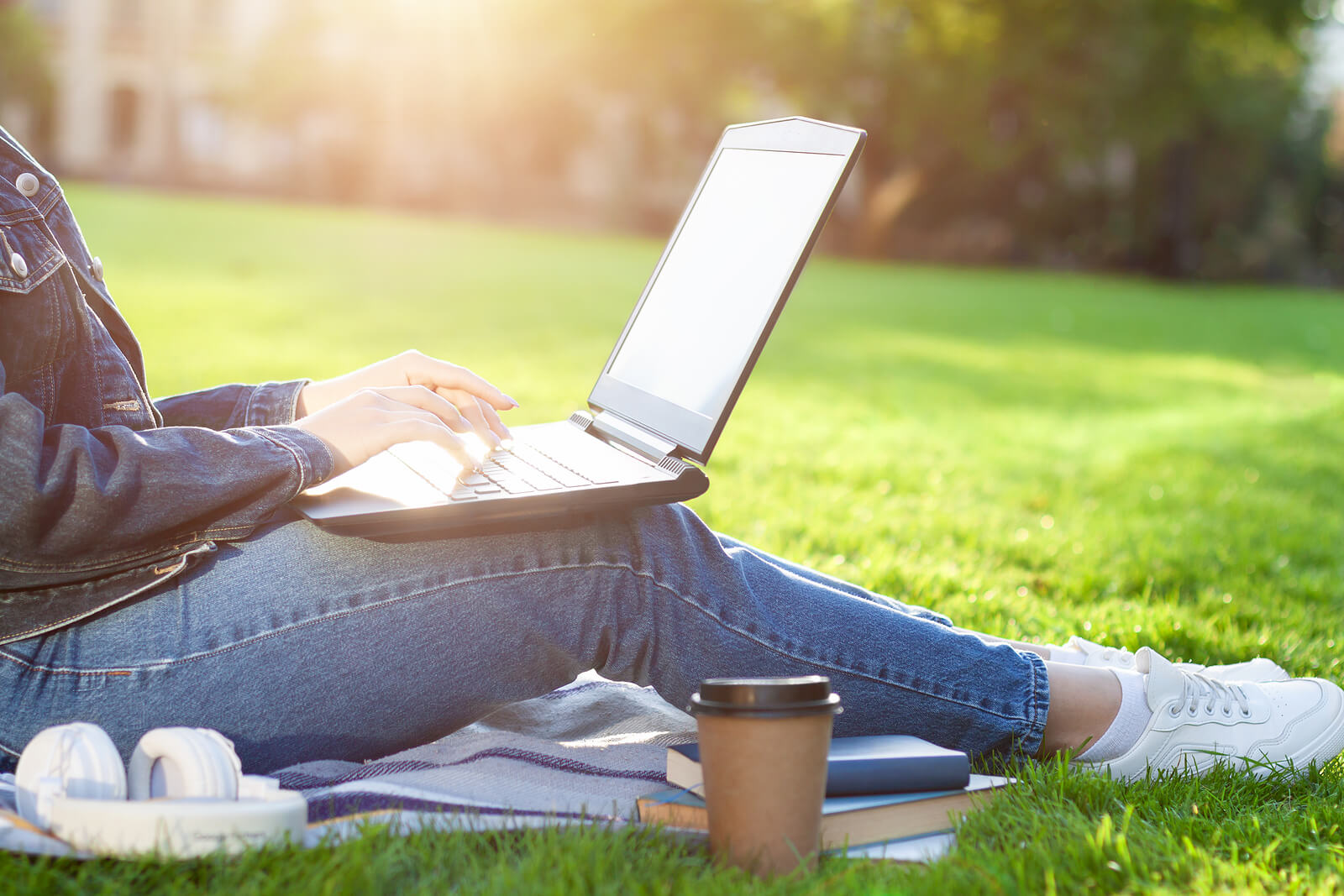 A woman sits outside on grass working on her laptop. Want to work through your issues through depth therapy in Houston, TX? Speak with an online therapist in Texas to see how online therapy can help you!
