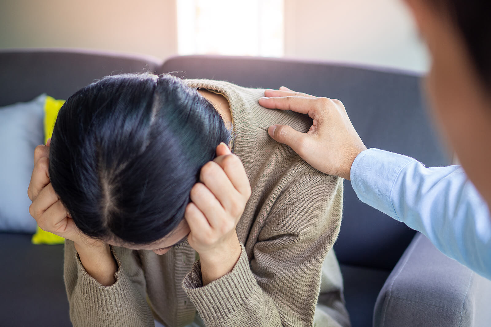 A woman is comforted by a man as she cries on a couch. Looking to learn the benefits that a trauma therapist can bring? Work through your developmental trauma in Austin, TX through trauma therapy today!