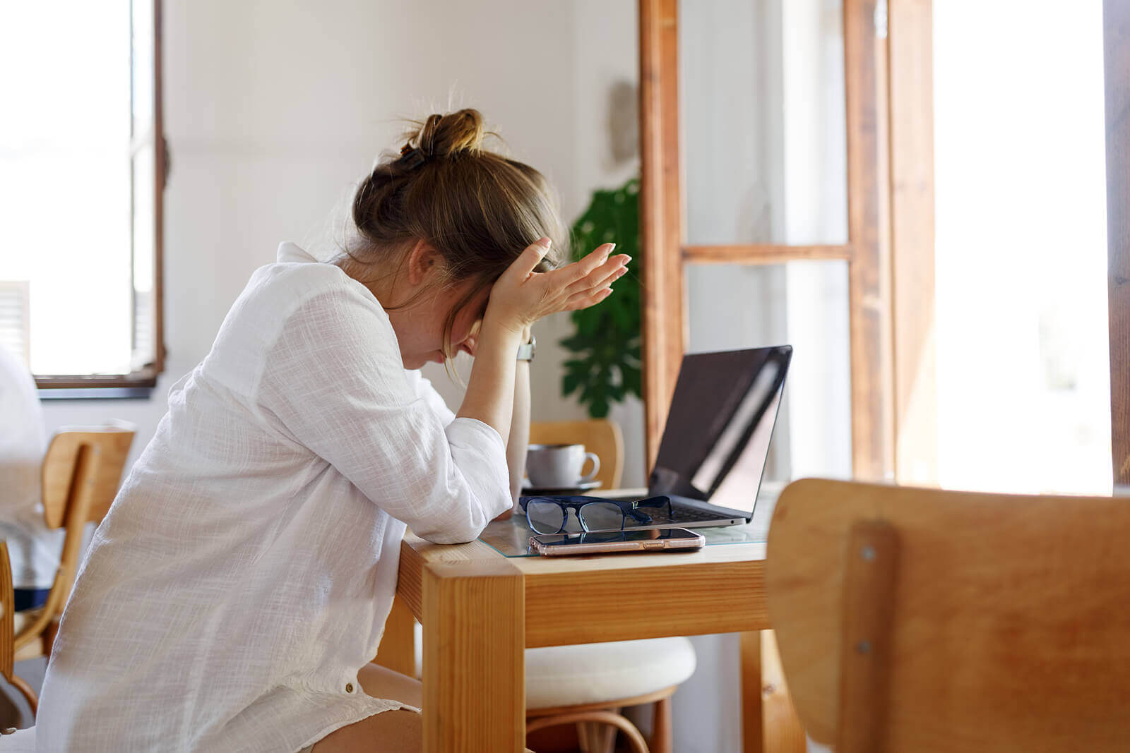 A frustrated woman sits at a desk with a laptop. Seeking online trauma therapy in Austin, TX? Speak with an online trauma therapist today.