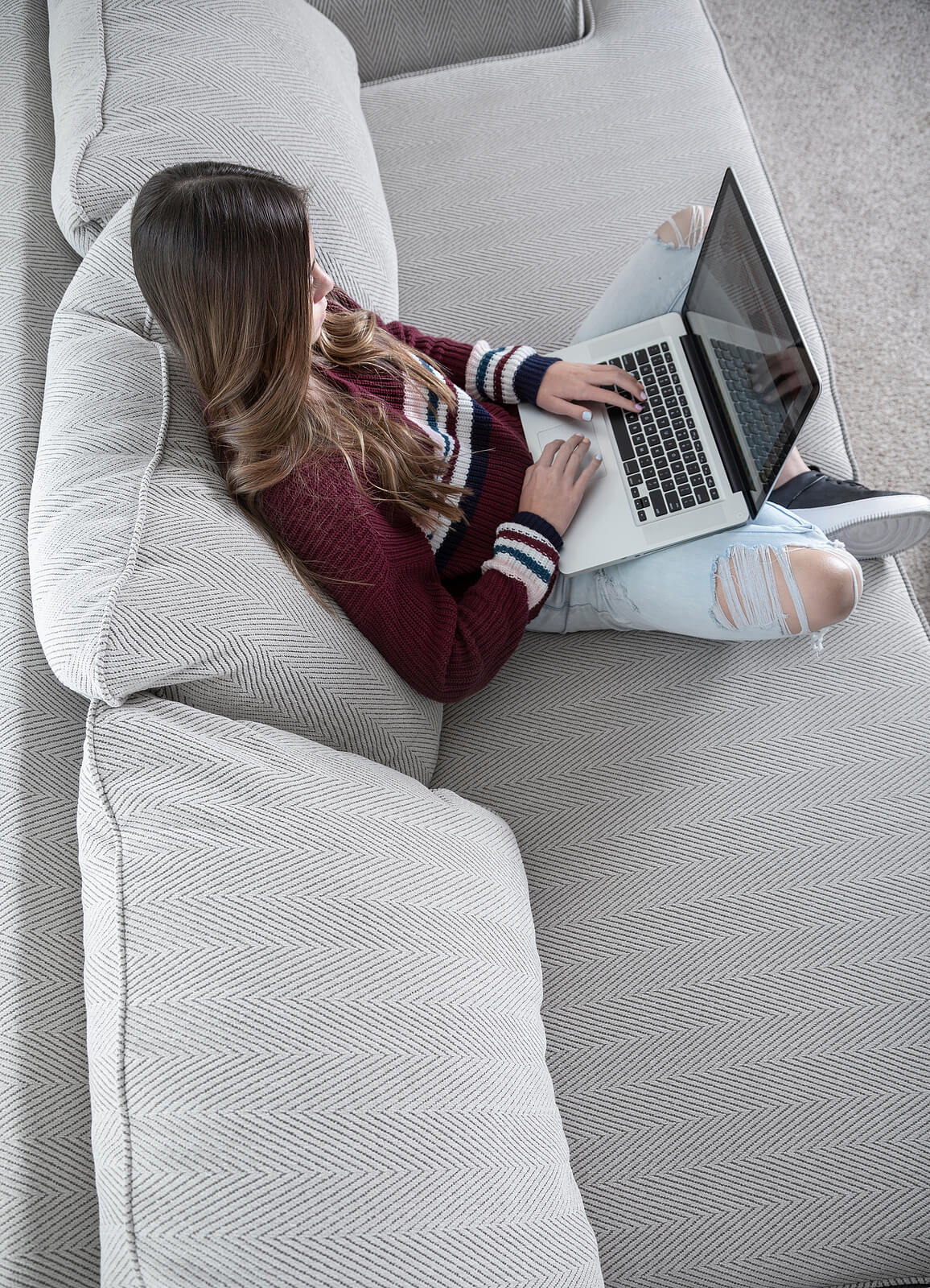 A woman sits on a couch while on her laptop. Looking to understand existential angst? Speak with a depth therapist in Texas and start depth therapy today!