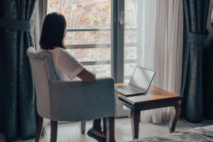 Woman sits on a chair looking outside thinking. Thinking about getting trauma therapy in Texas? Our psychotherapy specialist can get you the help you need.