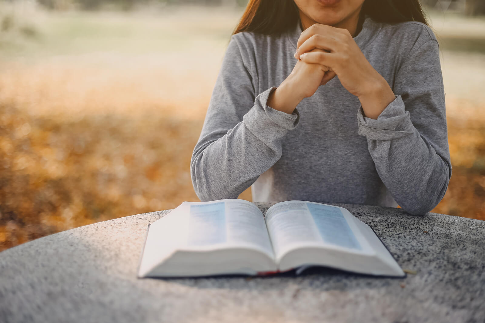 A woman sits with an open book sitting on a table. Is spiritual or religious trauma in Austin, TX keeping you down? Speak with a trauma therapist to see how trauma therapy in Texas can help. 