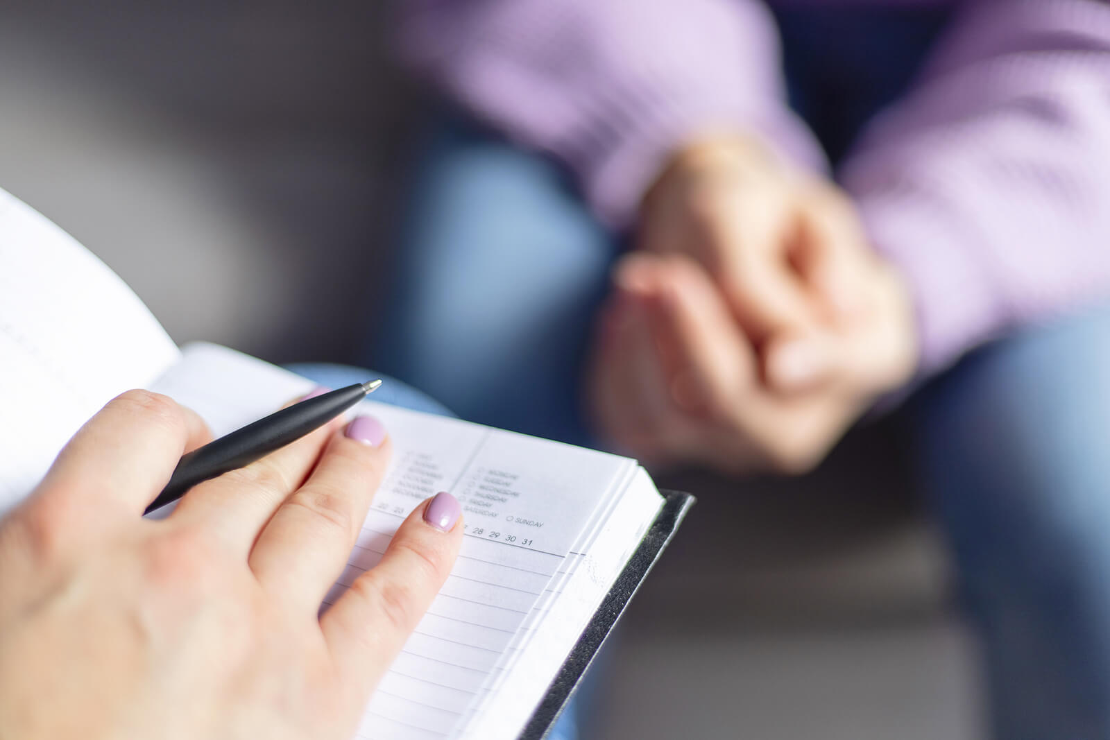 A therapist’s hand sits on a notebook while in a session with a person on a couch. Want to take the step to work on your emotional abuse in Austin, TX? We specialize in trauma therapy in Austin, TX. Call today!
