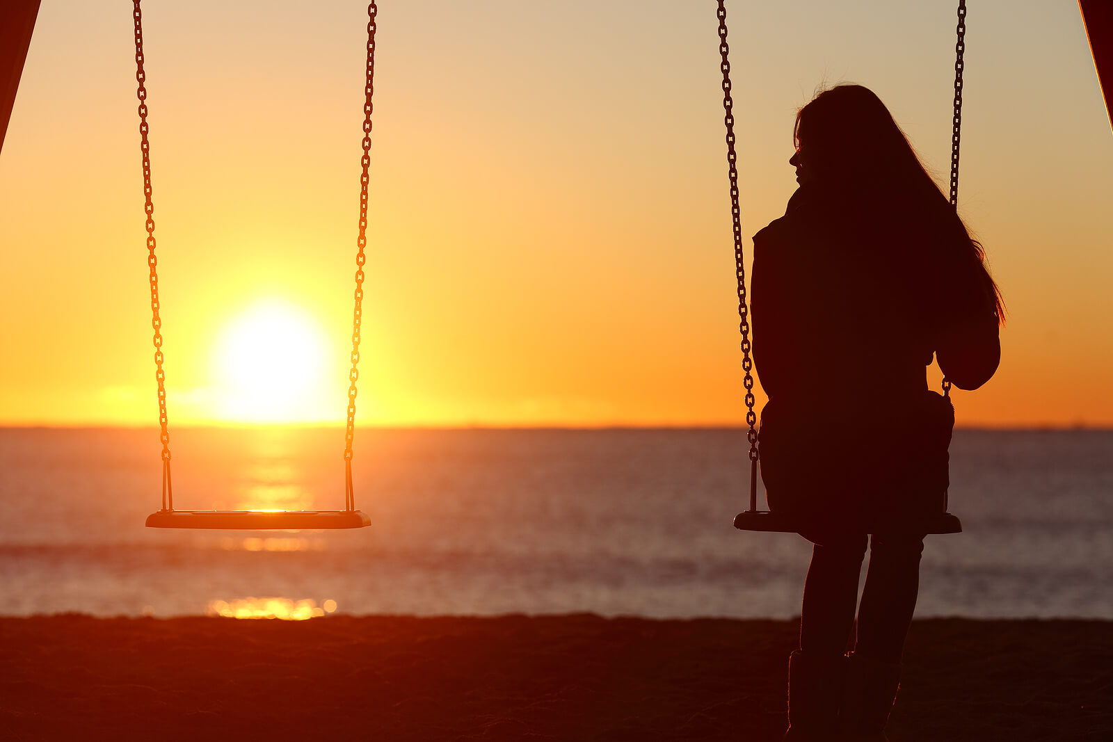 A woman sits on a swing set on the beach with the sun setting alone. Looking to improve your relationships? Individual therapy for relationship issues in Austin, TX can help you understand your relationships better. Speak with a relationship issues therapist in Texas today!