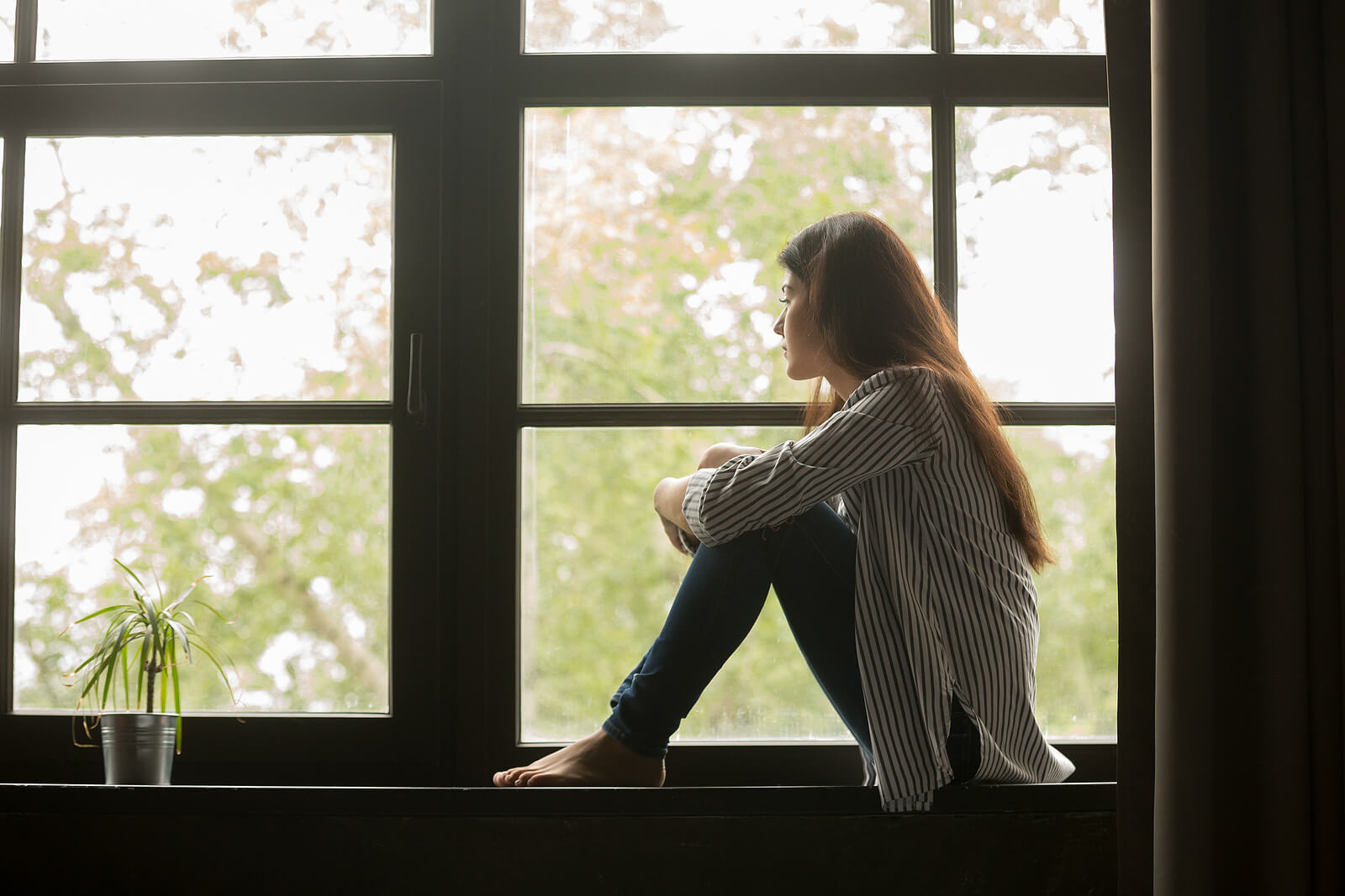 A woman sits near a window looking outside. Want to work through the emotional abuse you have dealt with in Austin, TX? Our trauma therapist can help move forward. Call today!