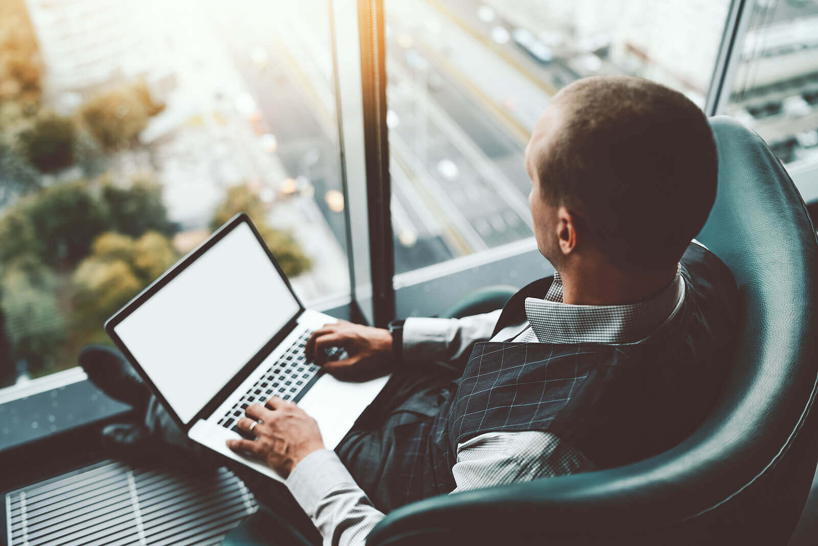 A man works on his laptop as he looks outside. Thinking about if depth psychotherapy is right for you? Speak with a depth therapist in Texas and learn more about it today!
