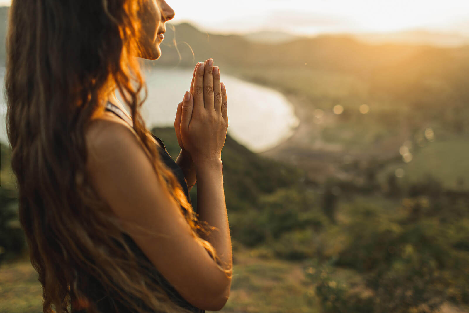 A woman holds her hands together praying outside. Want to move past your spiritual or religious trauma in Austin, TX? Speak with a trauma therapist in Texas to see how trauma therapy can help!