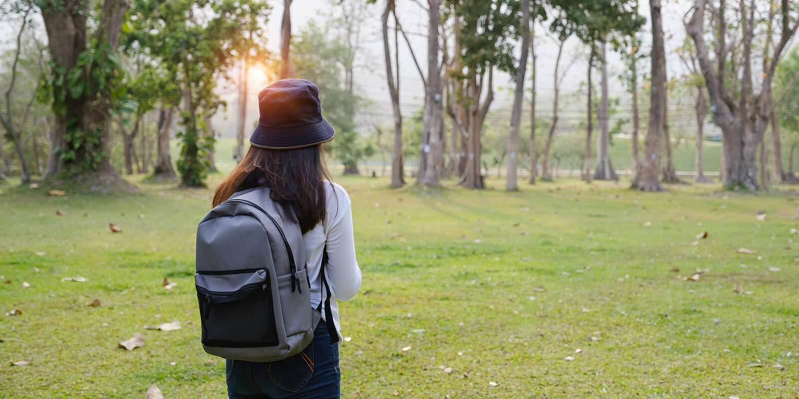 A woman stands near a bunch of trees in the grass in a park. Looking to get past your trauma through online trauma therapy in Austin, TX? An online trauma therapist can get you the help you need by reaching out.
