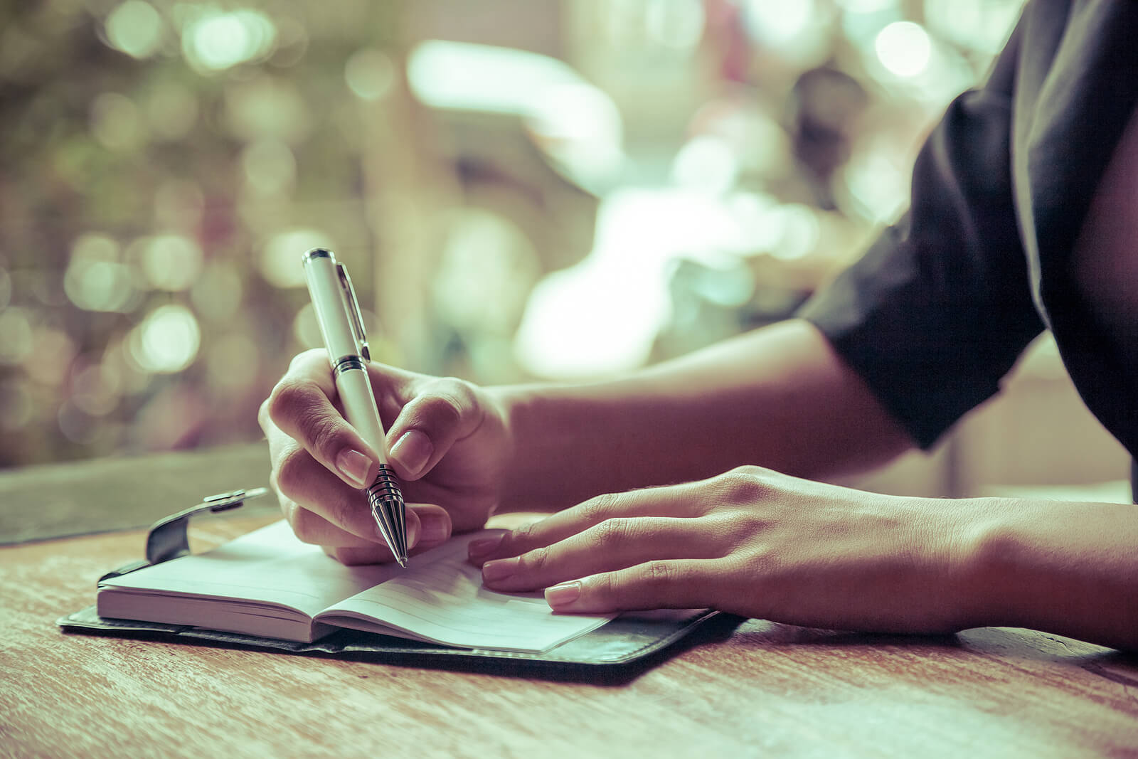 A person sits at a table writing in a journal. Learn to get past your relational trauma in Austin, TX by speaking with a trauma therapist. Start trauma therapy in Austin, TX today! 