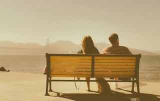 Image of a couple sitting on a bench on a sunny day. Discover how online trauma therapy in Austin, TX can help you cope with gaslighting and relational trauma.