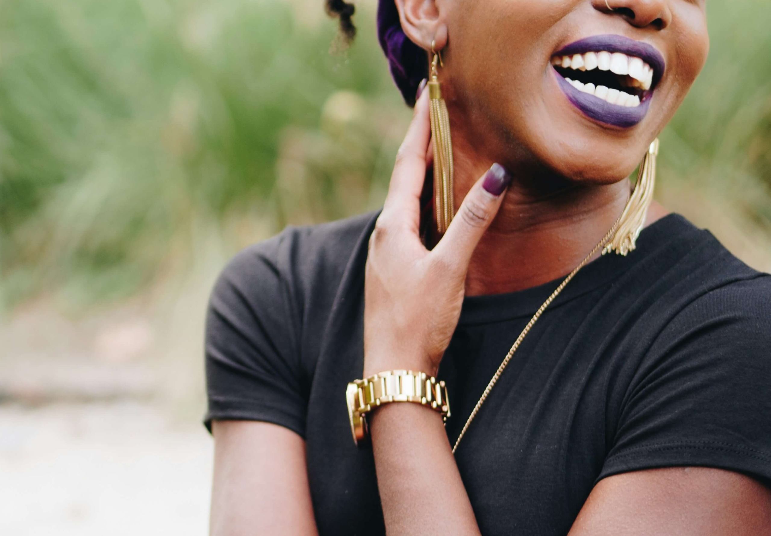 Image of a smiling African American woman wearing purple lipstick and standing outside. Relational trauma can be difficult to overcome, but with trauma therapy in Austin, TX you can learn healthy boundaries to protect yourself.