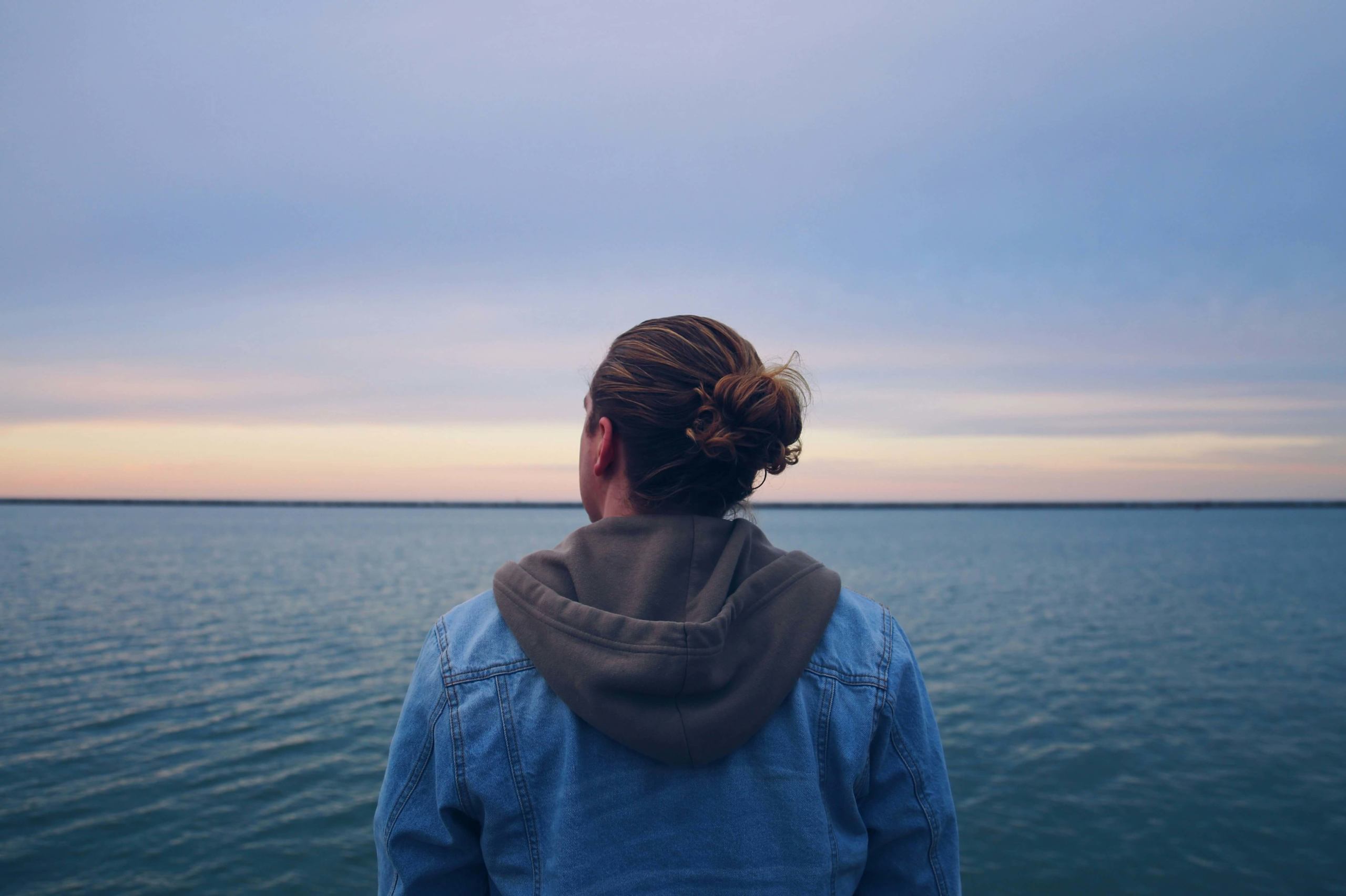 Image of a peaceful man looking out at a body of water while the sun rises. Overcome your past relational trauma with the help of trauma therapy in Austin, TX and boundaries.