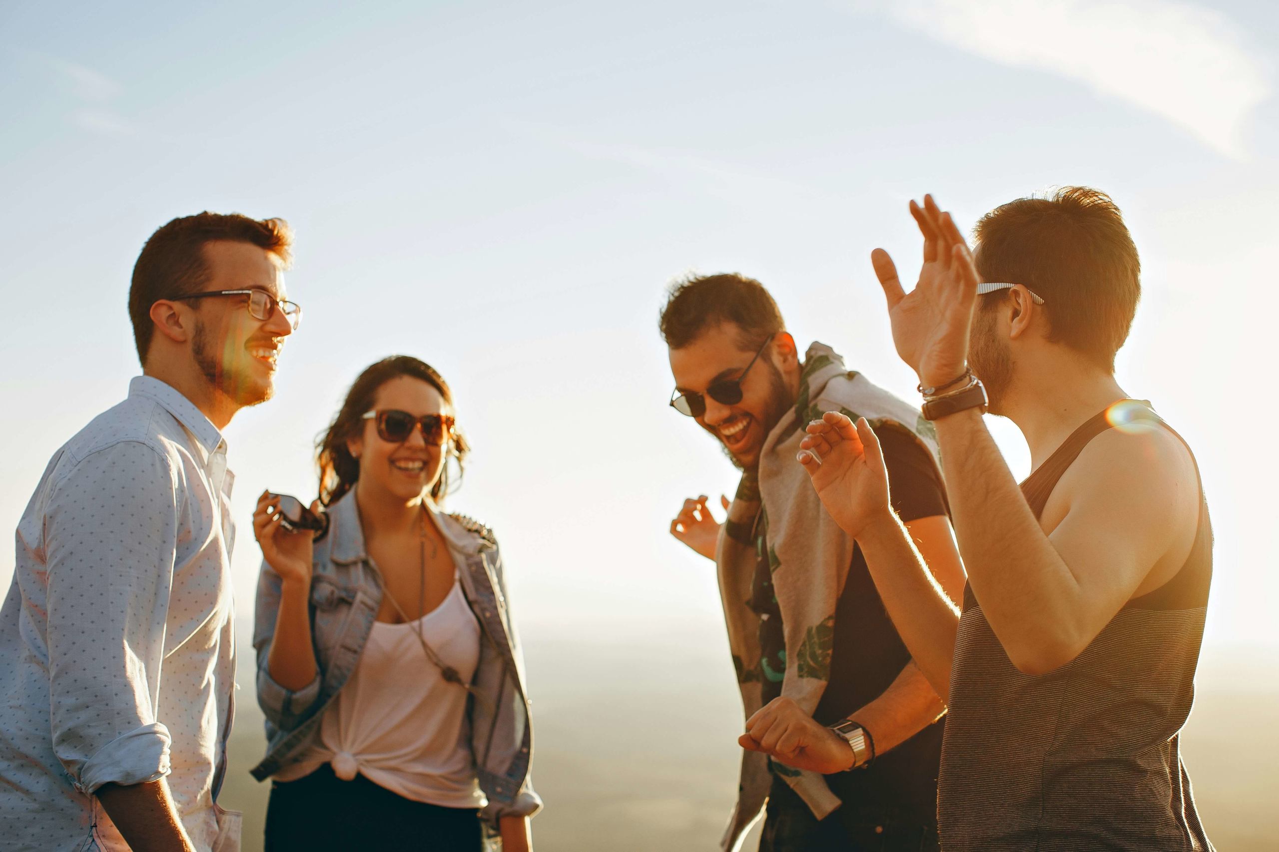 Image of a group of happy individuals standing outside laughing and smiling on a sunny day. Relationships are an important part of life. Meet with a skilled relational therapist in Austin, TX if you struggle to have meaningful relationships.
