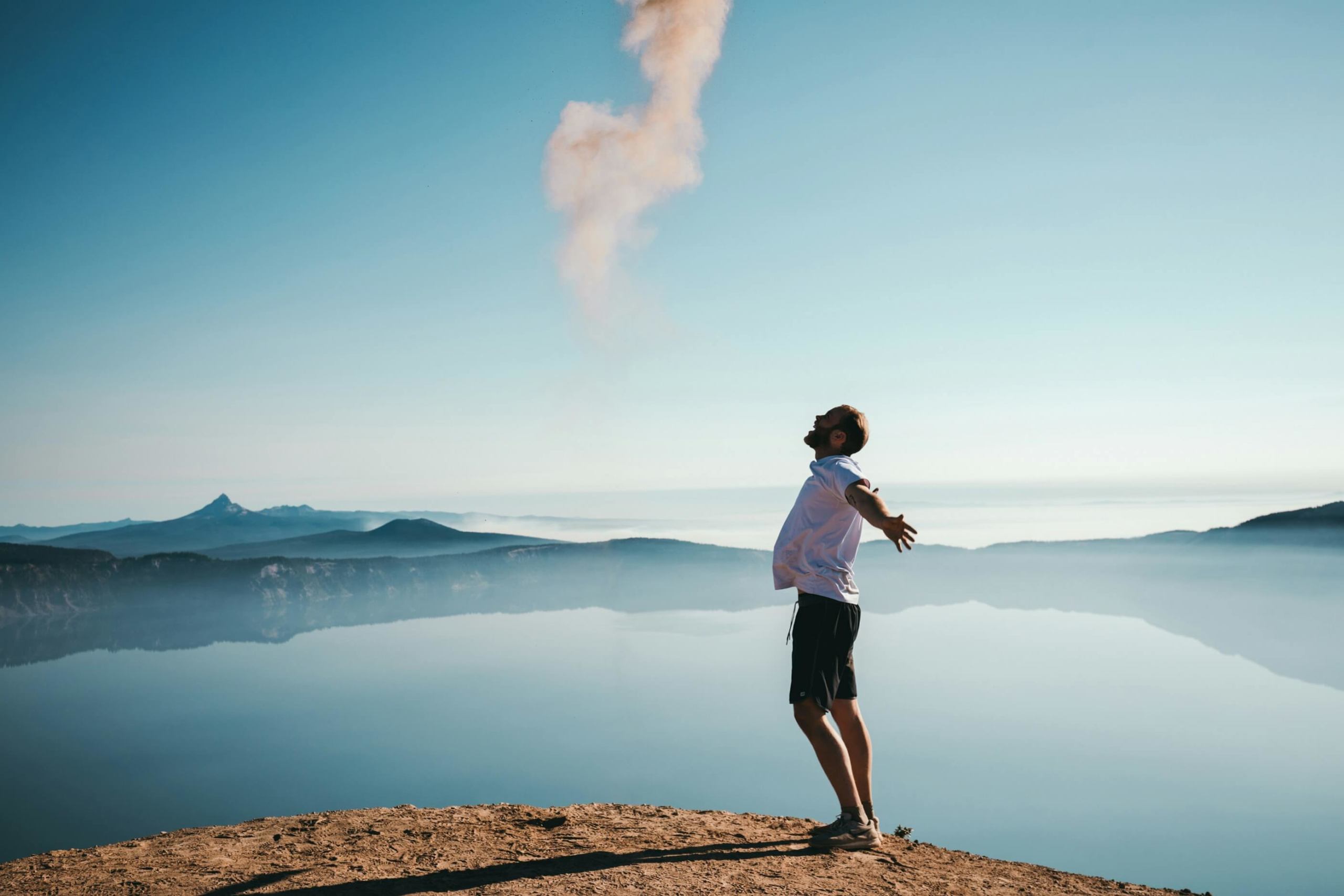 Image of a man standing on top of a mountain with his arms outstretched feeling free. Discover how HSP therapy in Austin, TX can help you embrace your unique traits.