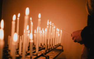 Image of someone standing in front of multiple lit candles. If you struggle with religious trauma in Austin, TX, discover how a trauma therapist can help you.