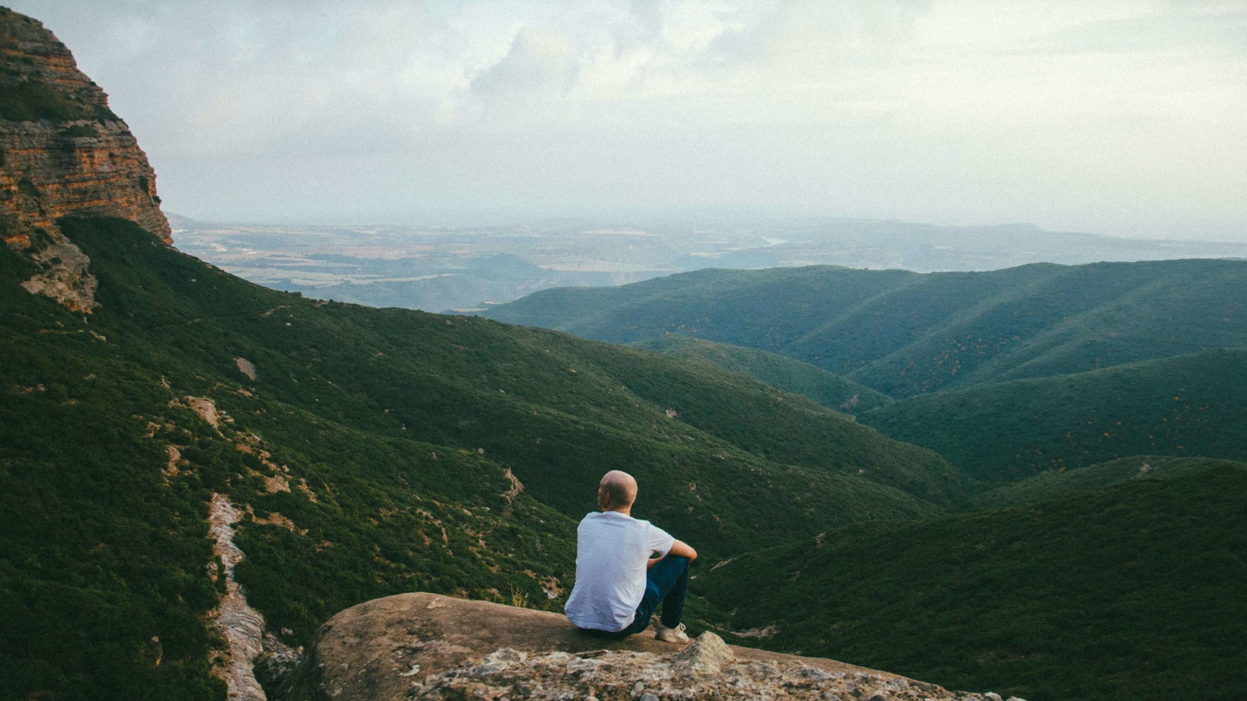 Image of a man sitting on rock overlooking a valley on a sunny day. Learn to manage your emotions with the help of empath counseling in Austin, TX.